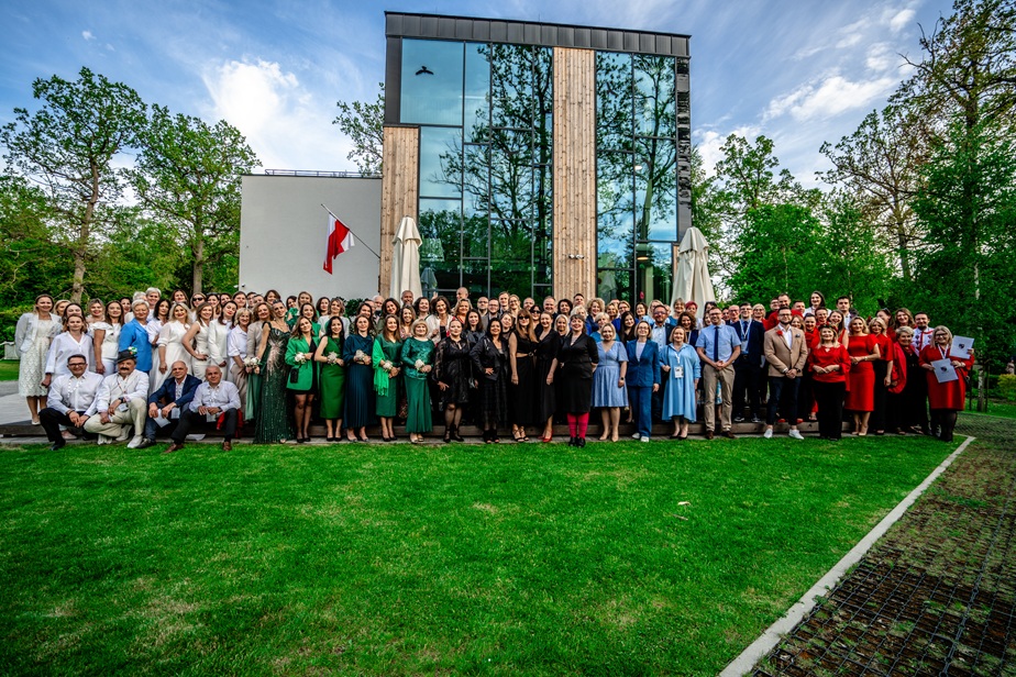 Zdjęcie przedstawia bardzo dużą grupę osób stojących na dworze przed budynkiem 