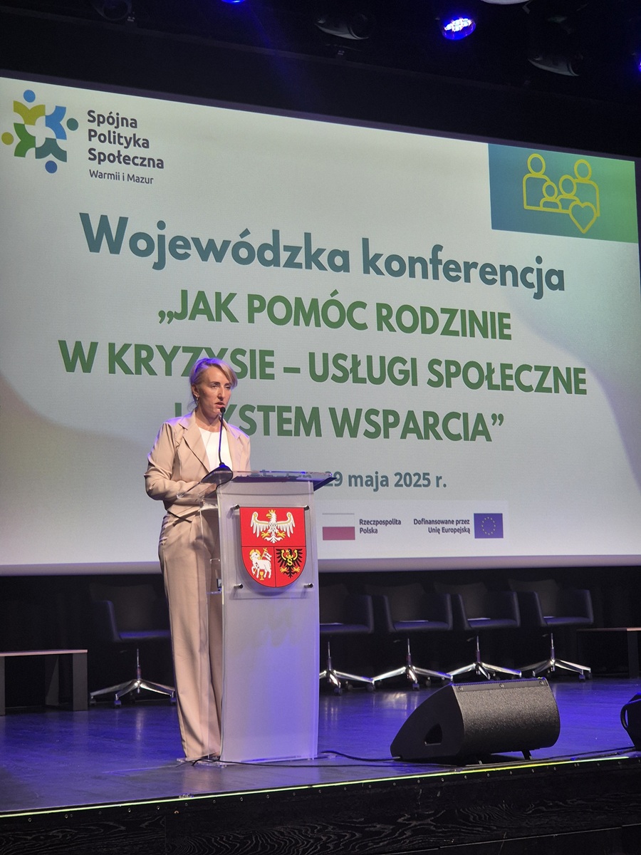 Zdjęcie przedstawia stojącą kobietę w sali  konferencyjnej