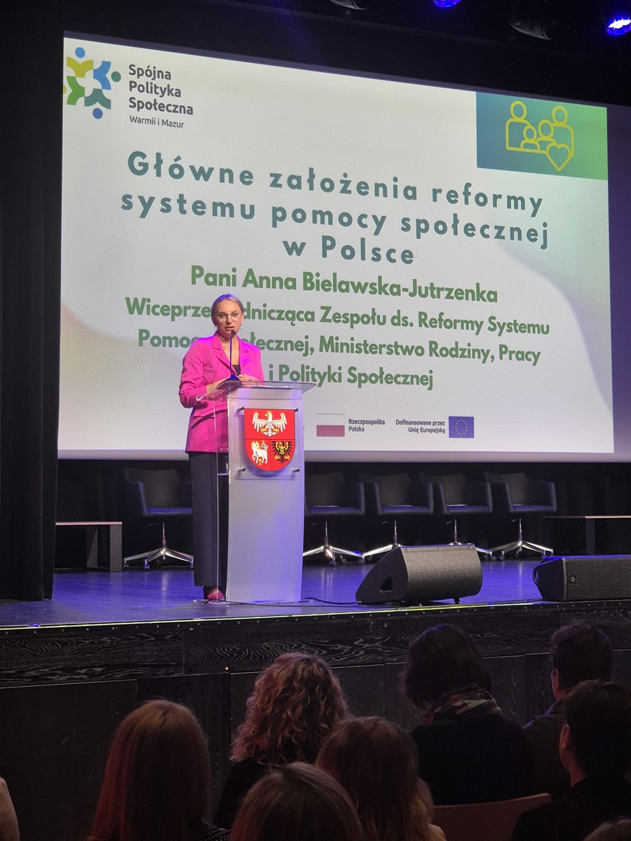 Zdjęcie przedstawia stojącą kobietę w sali  konferencyjnej