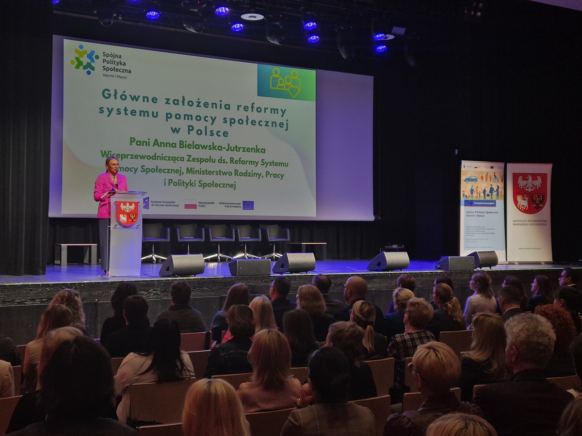 Zdjęcie przedstawia stojącą kobietę w sali  konferencyjnej