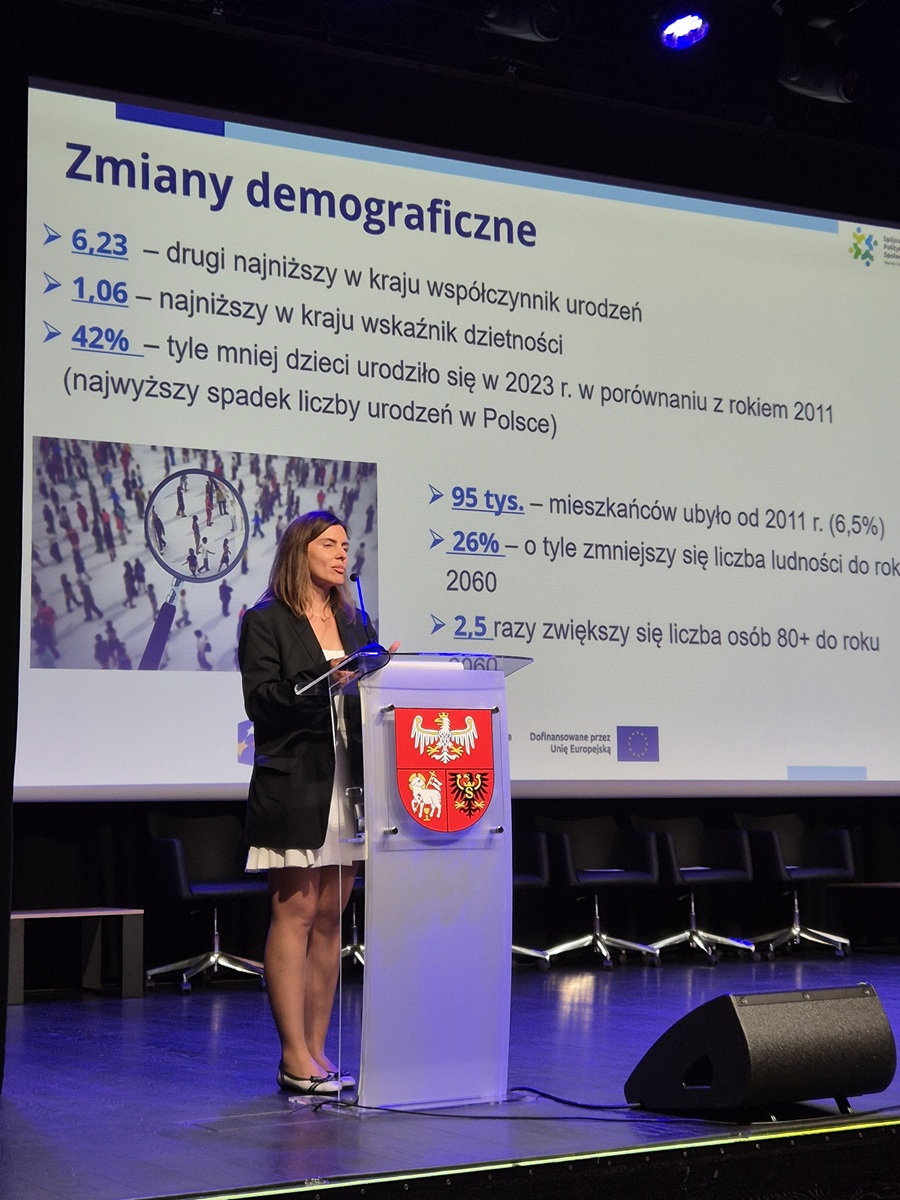 Zdjęcie przedstawia stojącą kobietę w sali  konferencyjnej