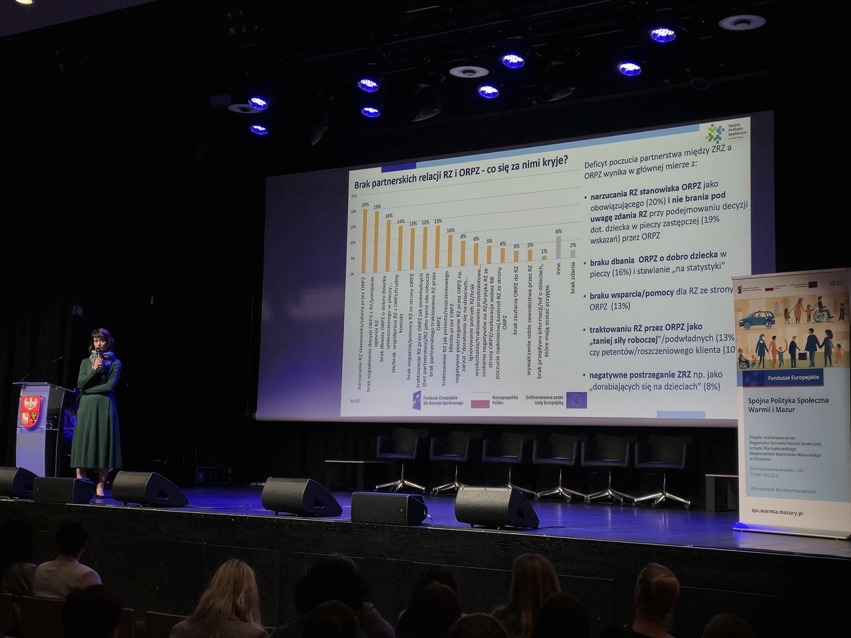 Zdjęcie przedstawia stojącą kobietę w sali  konferencyjnej