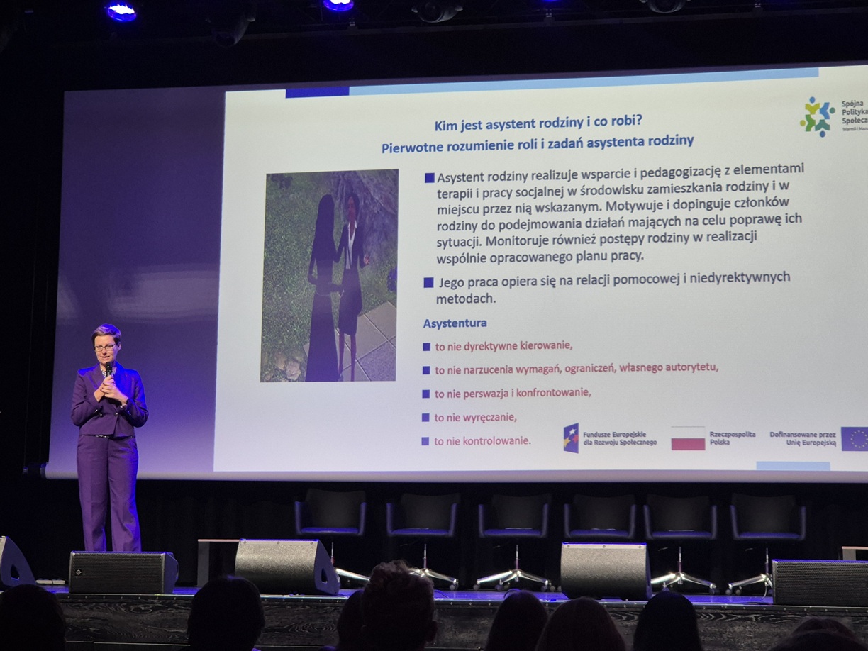 Zdjęcie przedstawia stojącą kobietę w sali  konferencyjnej