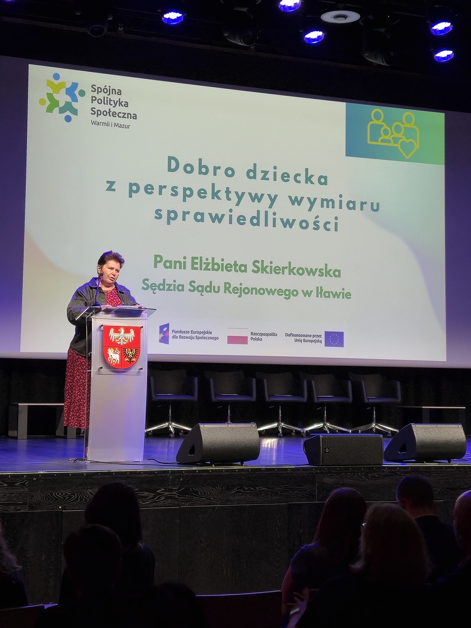 Zdjęcie przedstawia stojącą kobietę w sali  konferencyjnej