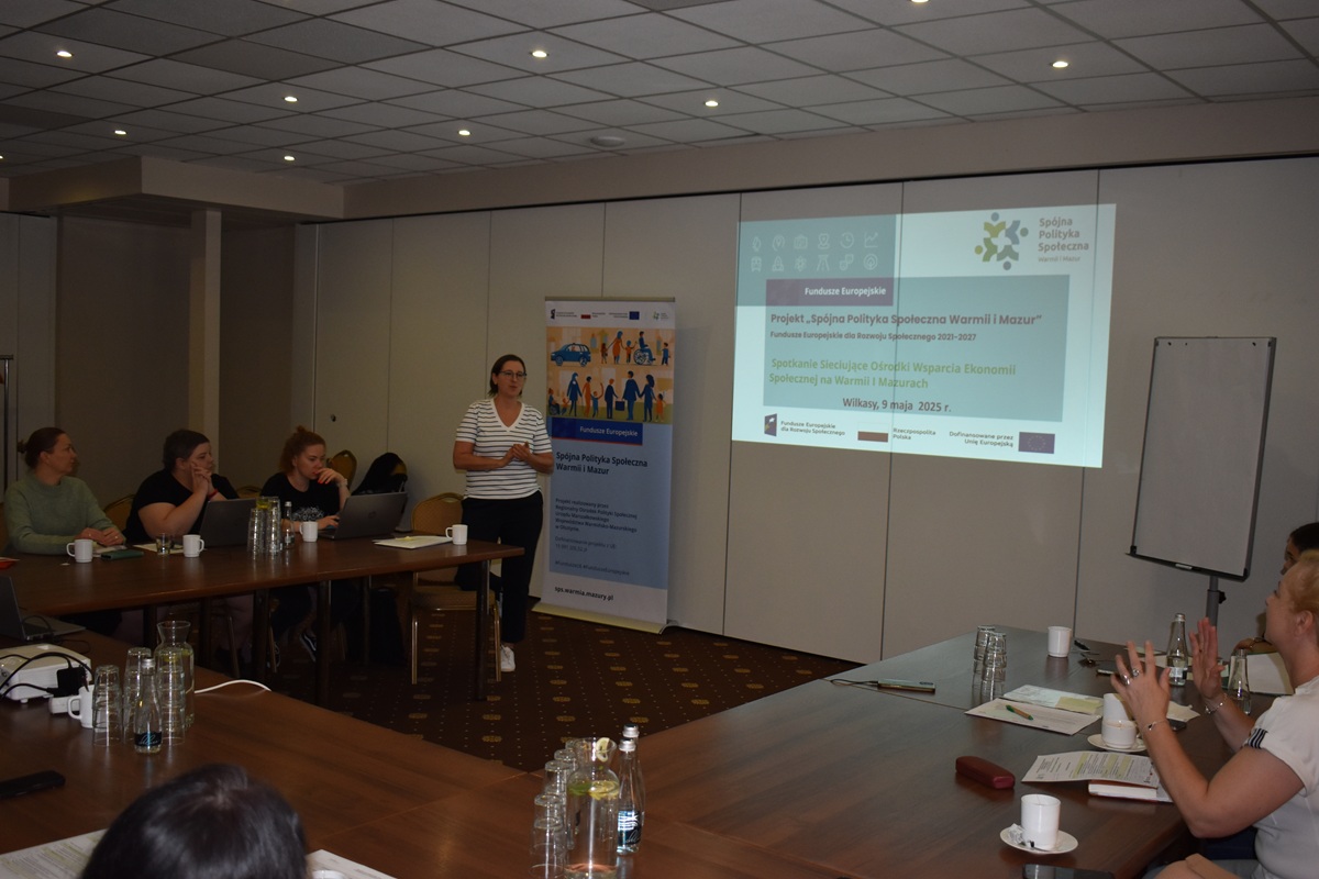 Zdjęcie przedstawia stojącą kobietę w sali  konferencyjnej